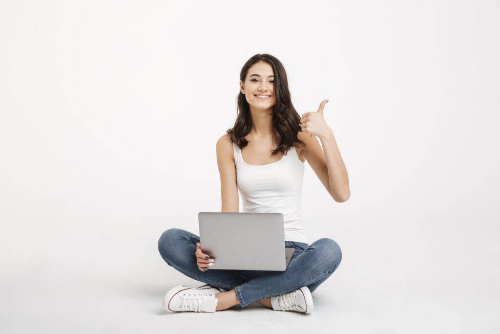 Portrait of a happy girl dressed in tank-top holding laptop