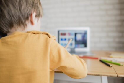vista-posterior-nino-aprendiendo-computadora-portatil-casa